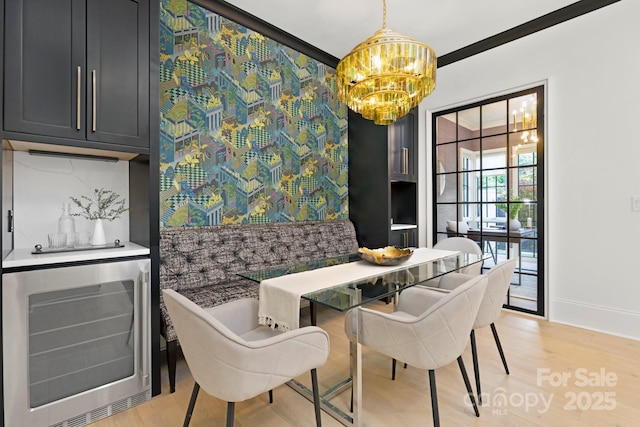 dining area with light wood-style floors, baseboards, wine cooler, and a notable chandelier