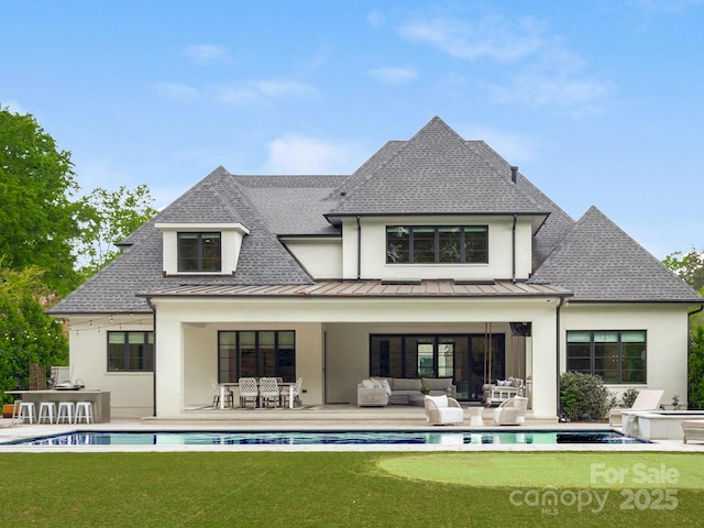 back of property with a standing seam roof, an outdoor kitchen, an outdoor living space, and roof with shingles