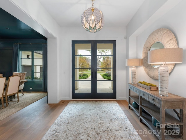 doorway with french doors, wood finished floors, and a notable chandelier