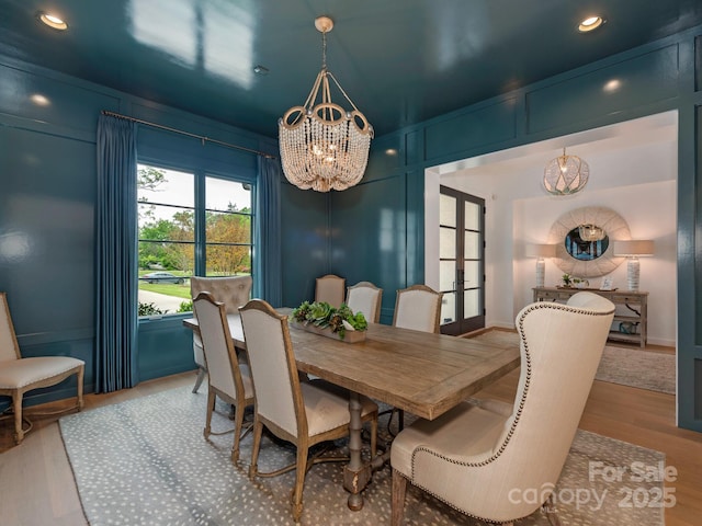 dining area with recessed lighting, an inviting chandelier, french doors, and wood finished floors
