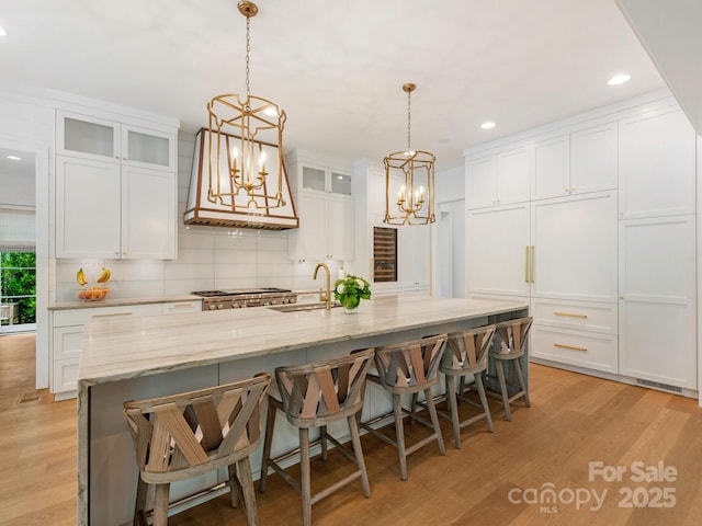 kitchen featuring white cabinetry, a chandelier, a sink, and light wood-type flooring