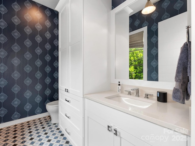 bathroom featuring vanity, wallpapered walls, and toilet