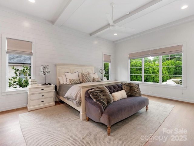 bedroom featuring baseboards, multiple windows, beamed ceiling, and light wood-style flooring