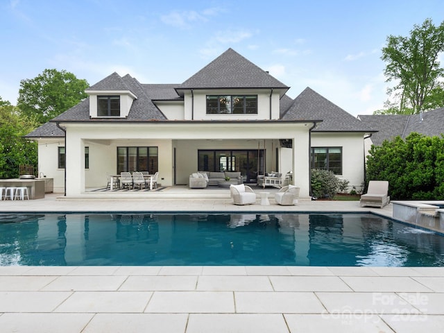back of house featuring an outdoor kitchen, stucco siding, outdoor lounge area, an outdoor pool, and a patio area