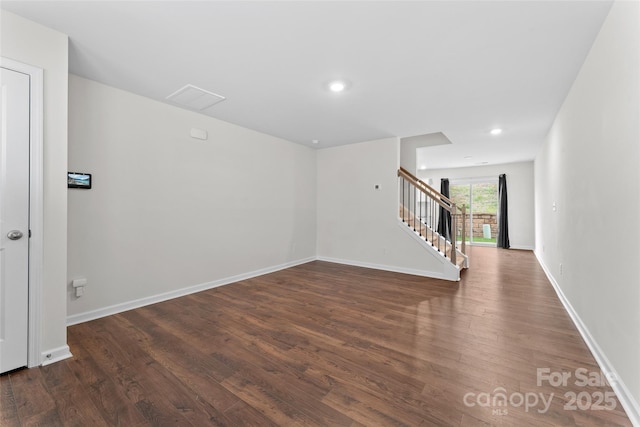 empty room featuring baseboards, wood finished floors, recessed lighting, and stairway
