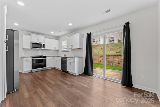 kitchen with stainless steel appliances, visible vents, decorative backsplash, and dark wood-style floors