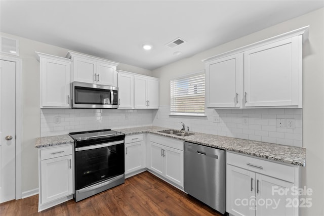kitchen with a sink, stainless steel appliances, visible vents, white cabinets, and dark wood-style floors
