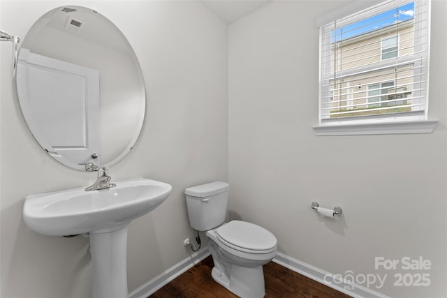 bathroom featuring plenty of natural light, toilet, wood finished floors, and baseboards