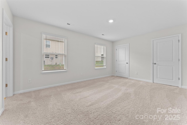 unfurnished bedroom with baseboards, light carpet, and visible vents