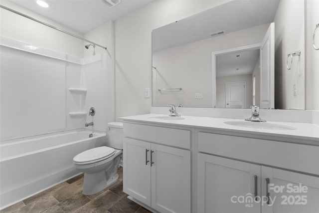 full bathroom featuring a sink, double vanity, toilet, stone finish floor, and visible vents