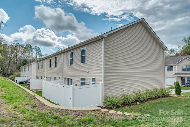 back of property with a lawn and fence