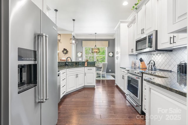 kitchen with white cabinets, a peninsula, tasteful backsplash, high end appliances, and dark wood-type flooring