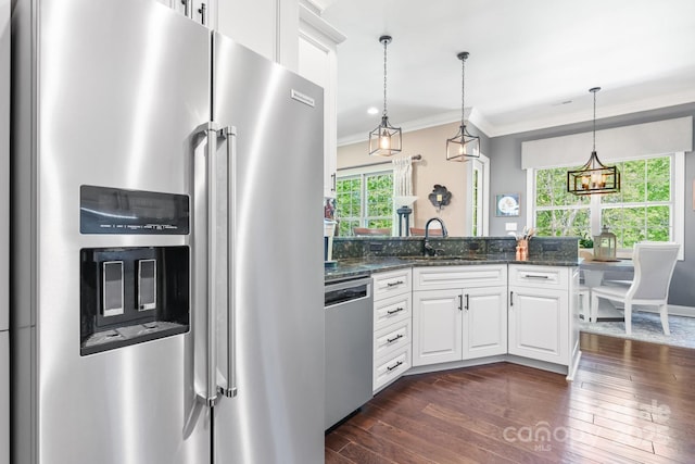 kitchen with dark stone countertops, ornamental molding, dark wood-style flooring, appliances with stainless steel finishes, and white cabinetry
