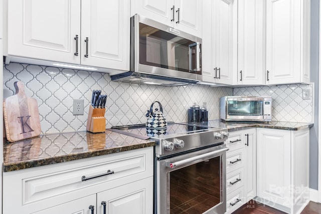 kitchen with white cabinets, stainless steel appliances, backsplash, and dark stone counters
