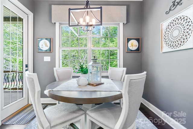 dining area with wood finished floors, baseboards, and a notable chandelier