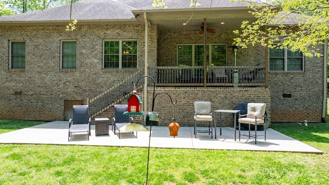 back of property with ceiling fan, a lawn, brick siding, and a patio