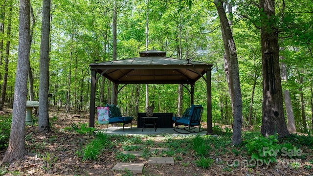 surrounding community with a gazebo, a view of trees, and a patio