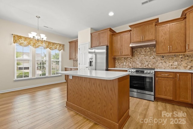 20135 Dovekie Ln, Fort Mill, SC 29707 - kitchen with brown cabinets, stainless steel appliances, light countertops, under cabinet range hood, and light wood finished floors