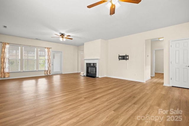 20135 Dovekie Ln, Fort Mill, SC 29707 - unfurnished living room featuring baseboards, a ceiling fan, a fireplace with flush hearth, and light wood finished floors