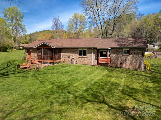 back of property featuring brick siding, a yard, central air condition unit, and a sunroom