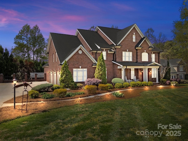 traditional-style house featuring a garage, a front yard, brick siding, and concrete driveway