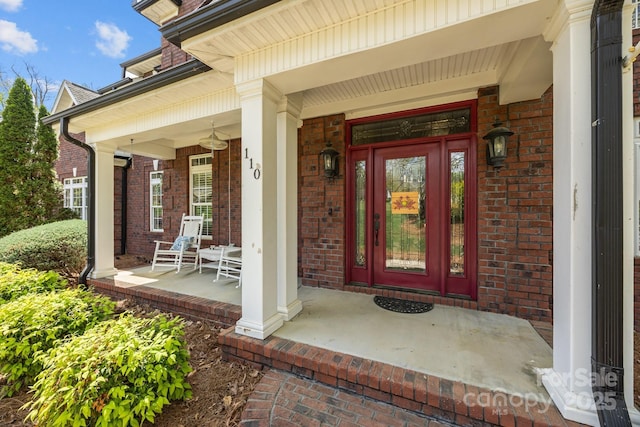 doorway to property with a porch and brick siding