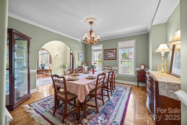 dining room featuring arched walkways, an inviting chandelier, and ornamental molding