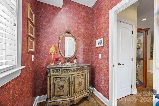 corridor with wood finished floors, a sink, and baseboards