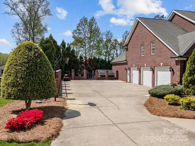 view of property exterior featuring brick siding, an attached garage, a shingled roof, and concrete driveway