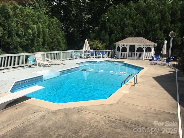 view of swimming pool featuring a diving board, an outdoor structure, fence, a patio, and a fenced in pool