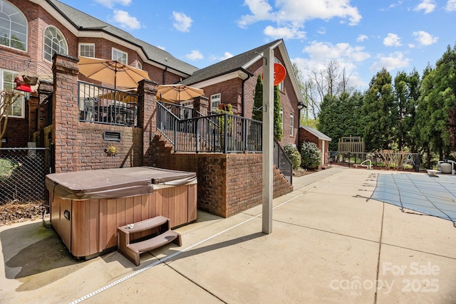 view of patio / terrace with stairway, fence, and a hot tub