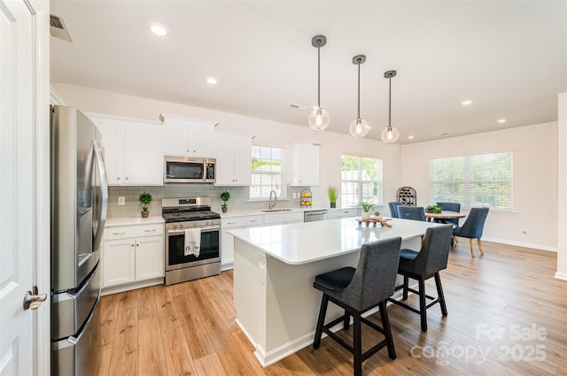 kitchen featuring tasteful backsplash, light wood-type flooring, a sink, light countertops, and stainless steel appliances