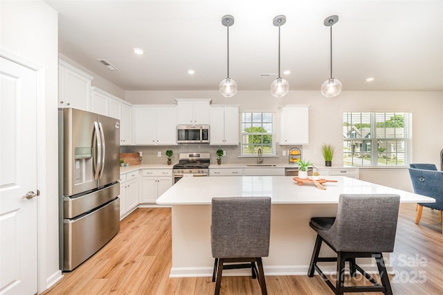 kitchen featuring a sink, light wood finished floors, light countertops, stainless steel appliances, and visible vents