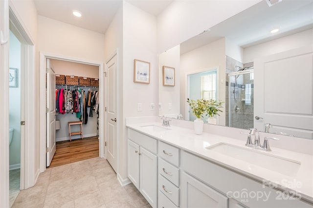 bathroom with a sink, a shower stall, double vanity, and a spacious closet