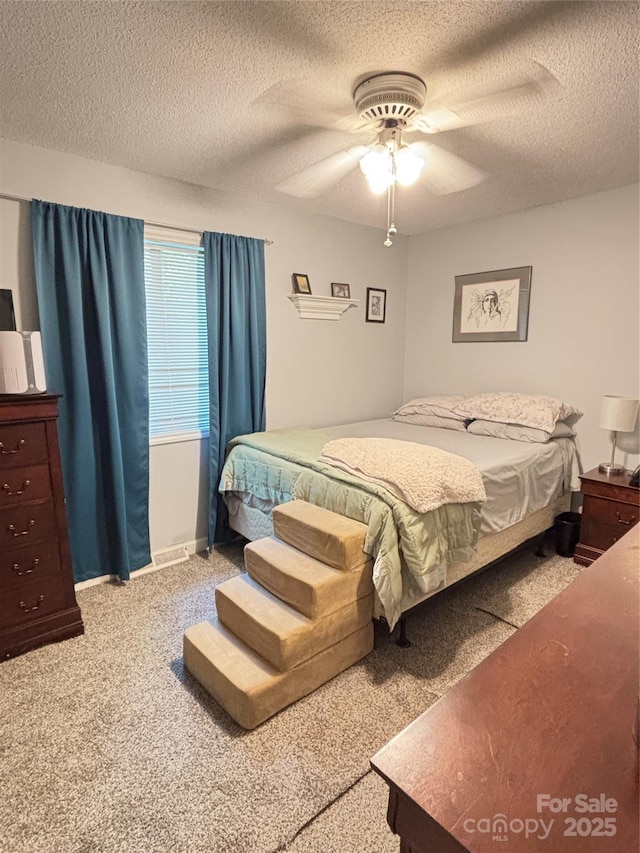 carpeted bedroom featuring a textured ceiling and a ceiling fan