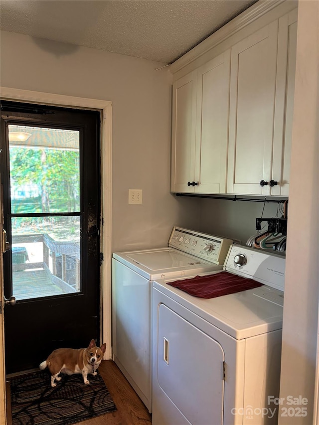 washroom with washing machine and clothes dryer, cabinet space, wood finished floors, and a textured ceiling