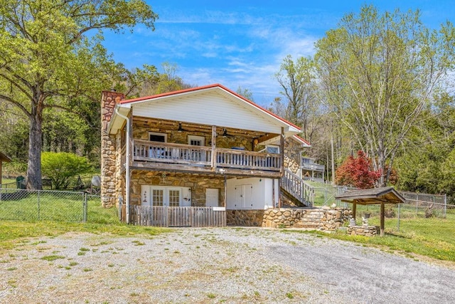 view of front of property with a chimney, fence, stone siding, stairs, and french doors