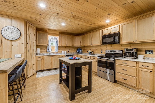 kitchen featuring light brown cabinetry, wood ceiling, wooden walls, black microwave, and stainless steel range with electric cooktop