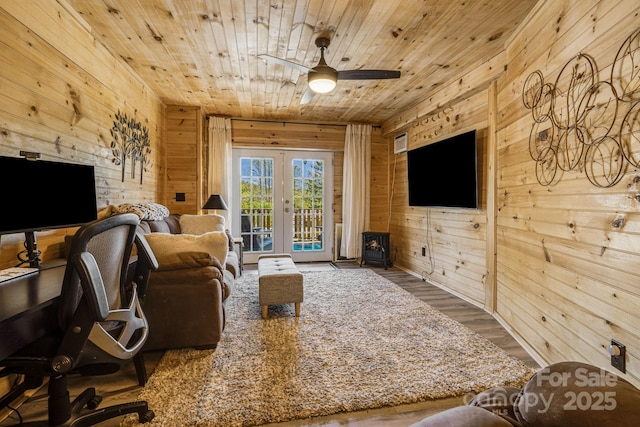 living room featuring a wood stove, wooden walls, and wooden ceiling