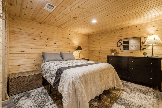 bedroom featuring wooden walls, visible vents, wood ceiling, and wood finished floors