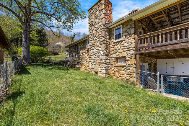 view of yard featuring fence and a balcony