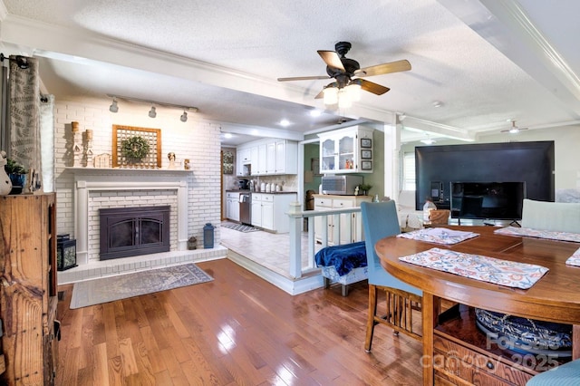 dining area with crown molding, a ceiling fan, wood finished floors, and a textured ceiling
