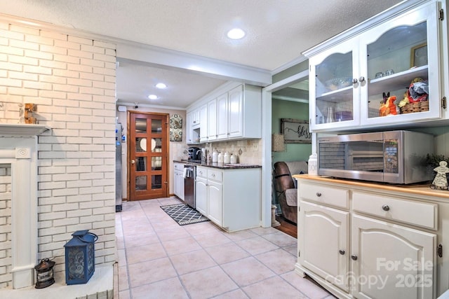 kitchen with light tile patterned flooring, white cabinetry, glass insert cabinets, crown molding, and appliances with stainless steel finishes