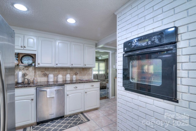 kitchen with dark stone counters, white cabinets, stainless steel appliances, and a textured ceiling