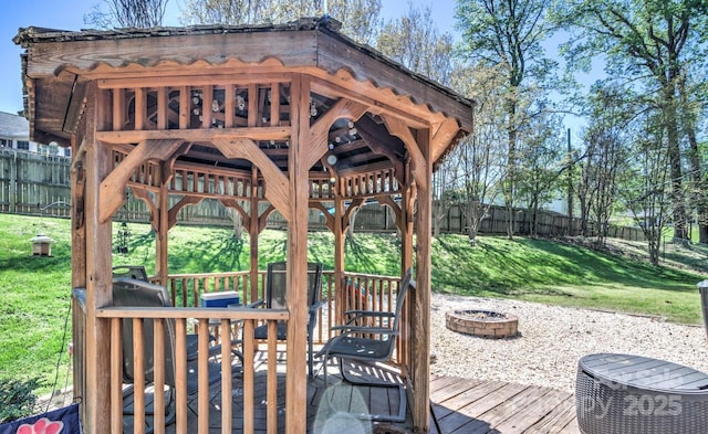 wooden terrace featuring a lawn, a fenced backyard, a fire pit, and a gazebo