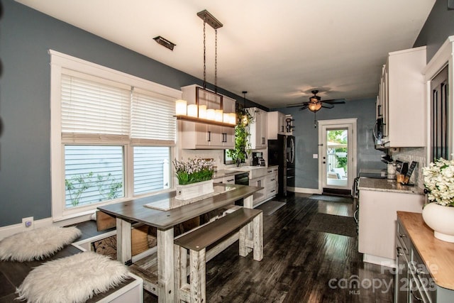 dining space with a ceiling fan, baseboards, and dark wood-style flooring