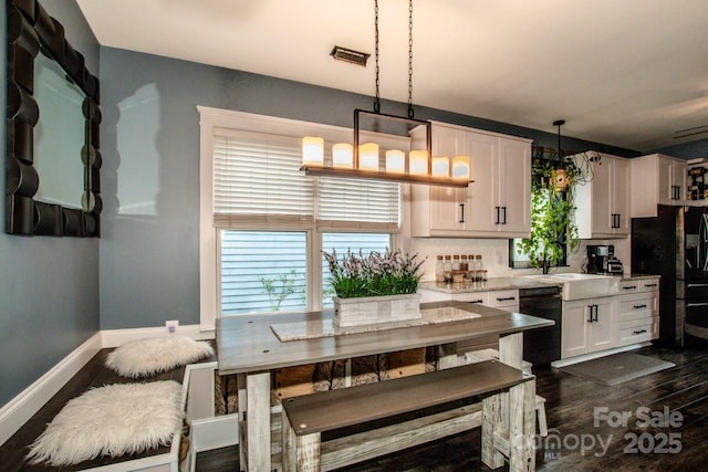 kitchen with dark wood-style floors, a sink, white cabinetry, decorative light fixtures, and black appliances