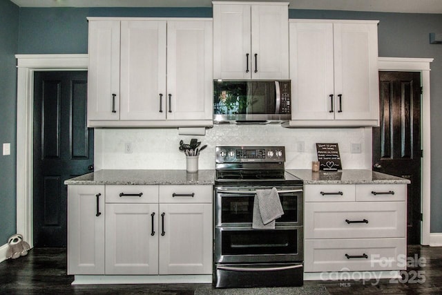 kitchen featuring stainless steel appliances, light stone countertops, dark wood-style flooring, decorative backsplash, and white cabinetry