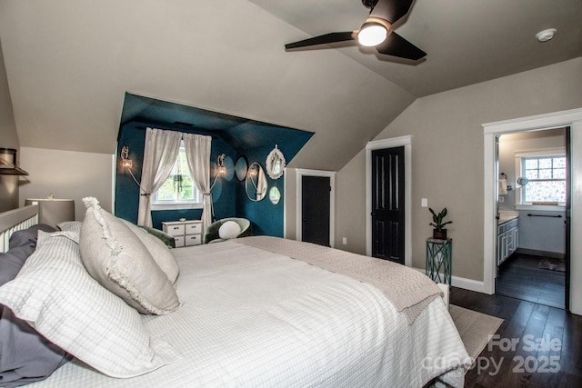 bedroom featuring dark wood finished floors, ensuite bath, multiple windows, and vaulted ceiling