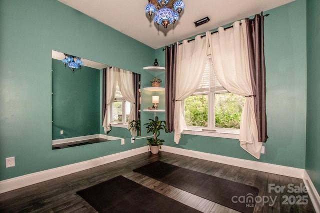 interior space featuring baseboards, an inviting chandelier, and wood finished floors